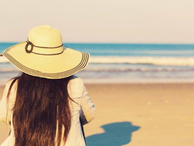 Woman in a hat sitting on the beach Woman in a hat sitting on the beach toward sunset
