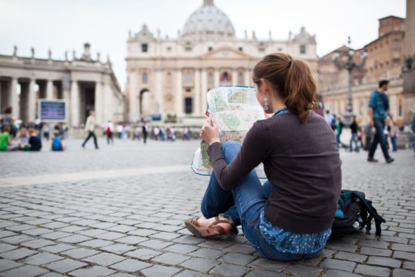 Pretty young female tourist studying a map at St. Peter's square Pretty young female tourist studying a map at St. Peter's square in the Vatican City in Rome
