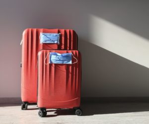 Two red luggages with protective masks. Two red luggages with protective masks to protect against coronavirus, global epidemic concept. Cancelled flights. Stop Travel.