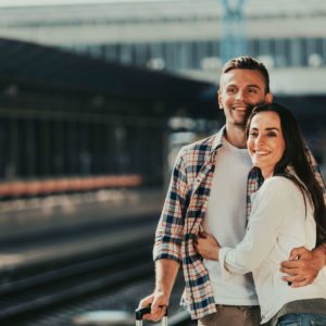 Valentinstag Nachtzüge Portrait of beaming woman embracing positive male while standing on railway station during sunny day